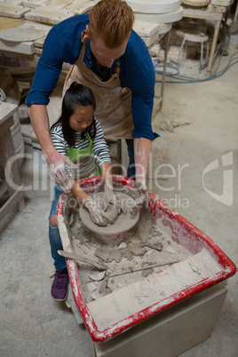 Male potter assisting girl in molding a clay