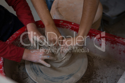 Female potter assisting boy in molding a clay