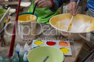 Female potter and boy painting bowl