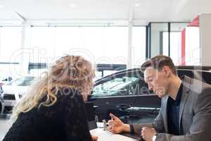 Salesman discussing over document with customer in showroom