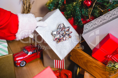 Santa keeping a gift on the wooden trolley