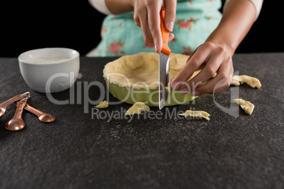 Woman slicing off extra dough from the mold
