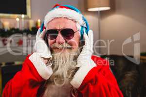 Santa claus listening to music on headphones at home