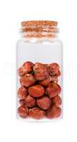 Hazelnuts in a glass bottle with cork stopper, isolated on white