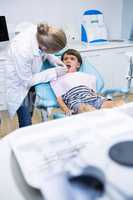 Dentist giving dental treatment to boy