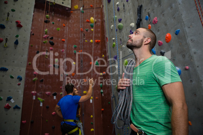 Trainer with rope looking up while athletes interacting in background