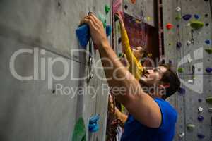 Confident athletes climbing wall in club