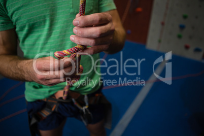 Midsection of athlete tying rope while standing in health club