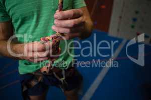 Midsection of athlete tying rope while standing in health club