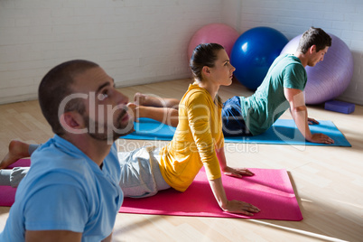 Yoga instructor with students practicing cobra pose in club
