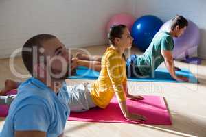 Yoga instructor with students practicing cobra pose in club