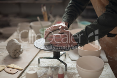 Mid section of male potter molding a clay