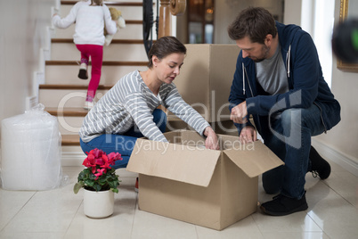 Couple opening cardboard boxes in living room