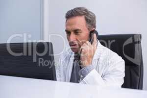 Dentist talking on phone while sitting by computer