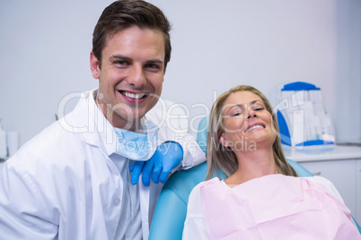 Portrait of smiling patient and dentist sitting on chair