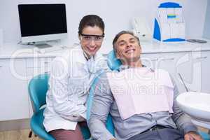 Portrait of smiling dentist and patient sitting on chair