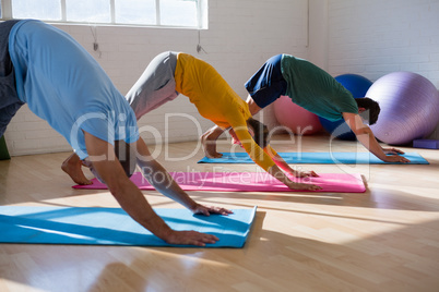 Instructor with students practicing downward facing dog pose in health club