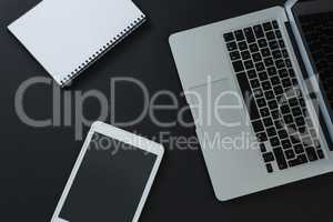 Laptop, digital tablet and organizer on black background