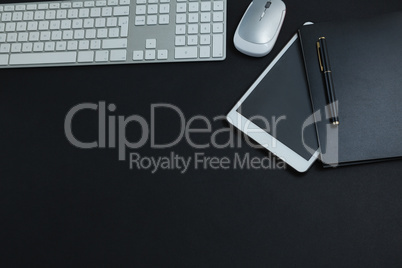 Keyboard, mouse, digital tablet, pen and organizer on black background