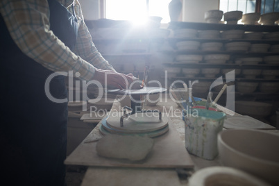 Male potter molding a clay on pottery wheel