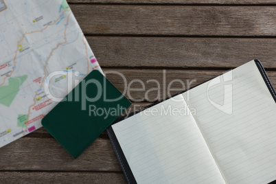 Open diary, passport and map on wooden table