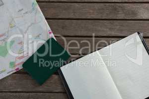 Open diary, passport and map on wooden table