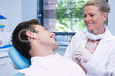 Patient looking at dentist while sitting on chair in medical clinic