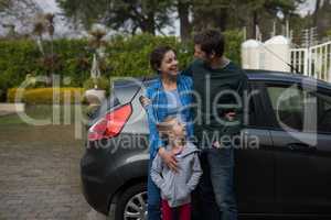 Father, mother and daughter standing near the car
