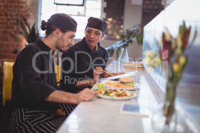 Young wait staff discussing over clipboard and food while sitting at counter
