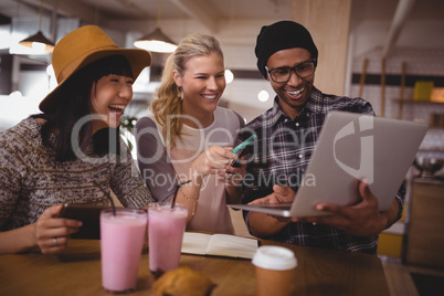 Man showing laptop to cheerful female friends at coffee shop