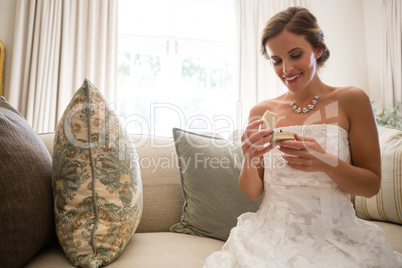 Low angle view of beautiful bride looking wedding ring while sitting on sofa