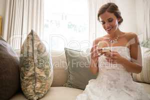 Low angle view of beautiful bride looking wedding ring while sitting on sofa