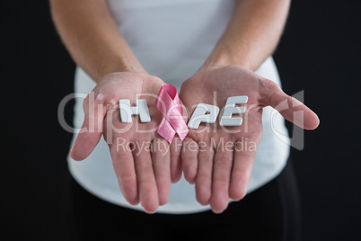 Mid section of woman holding pink ribbon with hope text