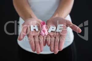 Mid section of woman holding pink ribbon with hope text