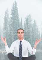 Business man meditating against misty river and trees