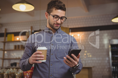 Businessman having coffee while using phone in cafe