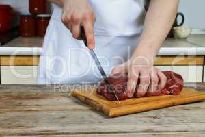 Butcher cutting pork meat on kitchen