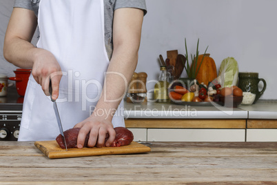 Man in the kitchen cutting a piece of meat