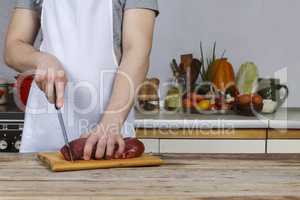 Man in the kitchen cutting a piece of meat