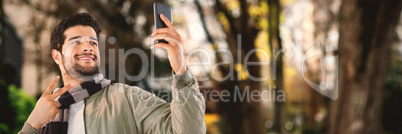 Composite image of smiling man taking selfie through mobile phone against white background