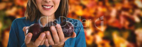 Composite image of portrait of woman holding plums