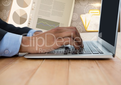 Business hand with laptop at desk with diagrams and charts