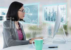 Businesswoman at desk with computer and bar charts interface graphics screens