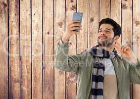 Man against wood with phone and scarf and coat