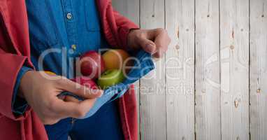 Person holding apples in jumper against wood
