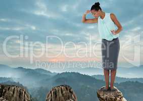 Businesswoman looking down from height on rock in mountains