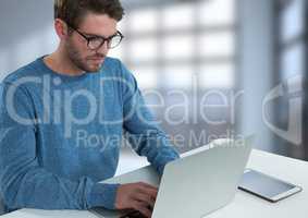 Businessman with laptop at desk with bright background