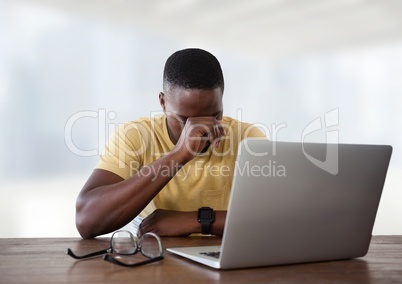 Tired Businessman at desk with laptop with bright background