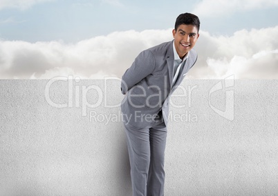 Businessman against wall with clouds