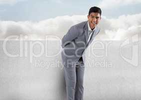 Businessman against wall with clouds